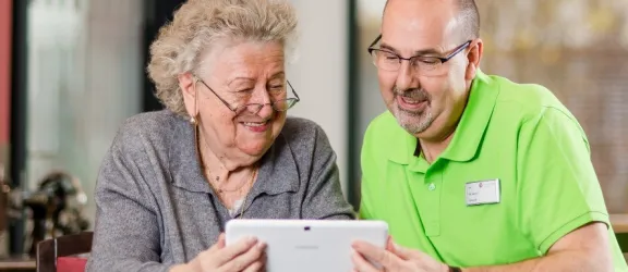 Seniorin und Pfleger schauen in ein Tablet bei Senioren-Tagespflege Bayreuth