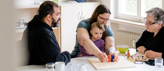 Eine Familie spielt am Tisch im Rahmen der ambulanten erzieherischen Dienste