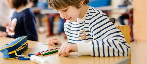 Autistischer Junge sitzt am Tisch im Klassenzimmer