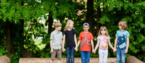 Schulkinder stehen lachend im Garten vom Hort nebeneinander