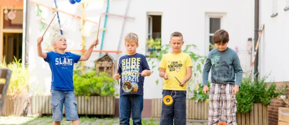 Vier Jungs im Kinderhort spielen Diabolo