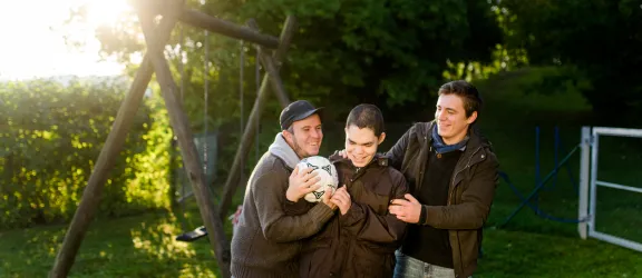 Angehnde Heilerziehungspfleger spielen Fußball mit Junge mit Behinderung