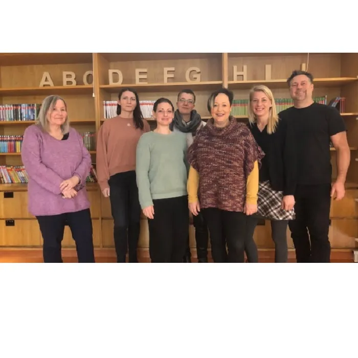 Sieben Lehrer*innen stehen vor einem Bücherregal