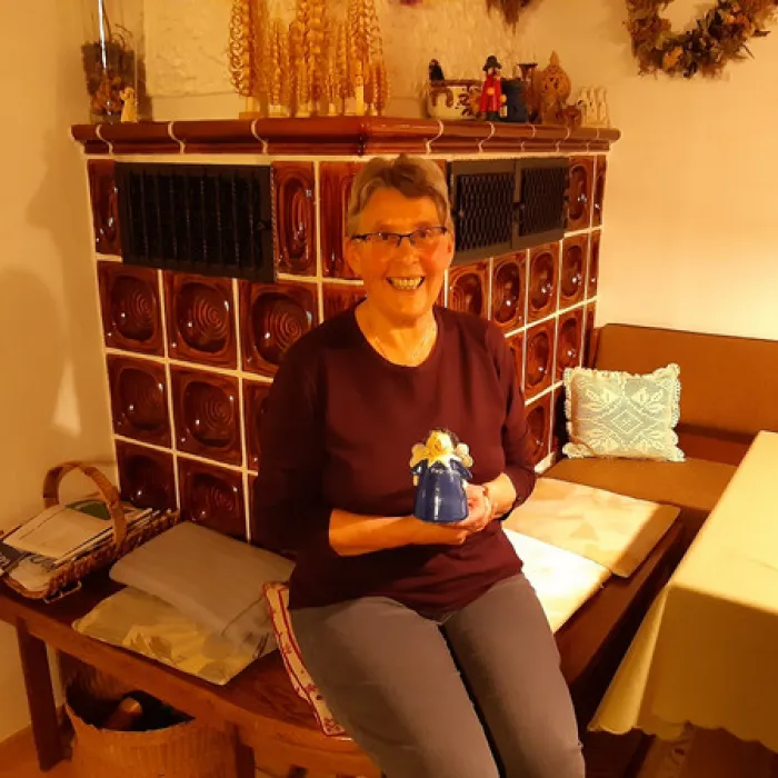 Ilse Zeitler sitzt mit dem TOV-Engel vor dem Kamin