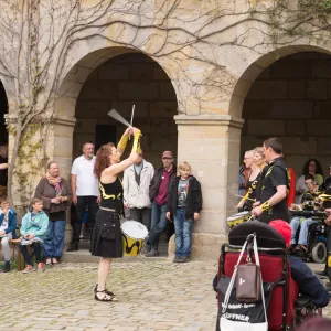 Menschen stehen im Hof und schauen einer Trommelgruppe zu