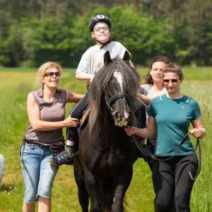 Kind sitzt auf Pferd.