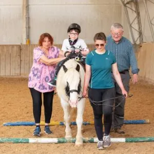 Kind sitzt auf Pferd.
