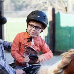 Kind sitzt auf Pferd.
