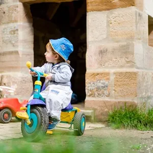 Krippenkind beim Dreiradfahren