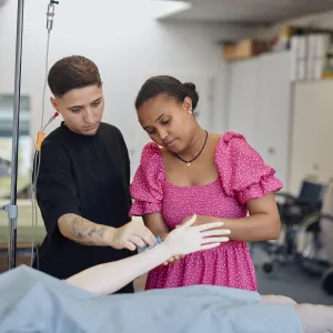 Zwei Pflegeschüler üben an der Pflegepuppe