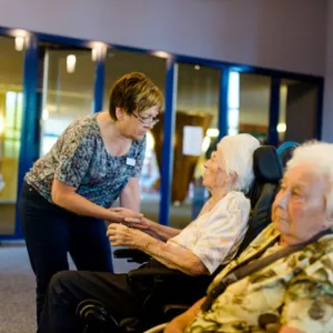 Mitarbeiterin des Mühlhofer Stift Bayreuth im Gespräch mit Seniorin im Rollstuhl