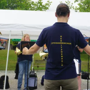 Dirigent steht mit dem Rücken im Bild, dahinter das Orchster