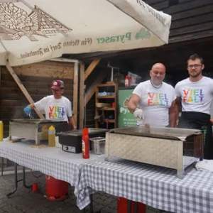 Drei Menschen stehen am Grill