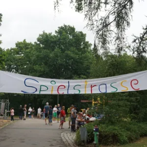 Weg am Auhof. Darüber ein großes Schild mit Hand geschrieben. Darauf steht Spielstraße