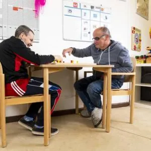 Zwei Männer sitzen an einem Tisch und spielen etwas