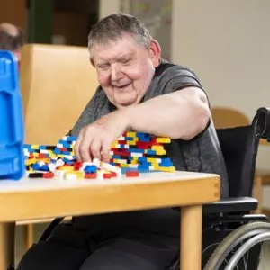Ein Mann sitzt am Tisch und spielt mit Lego