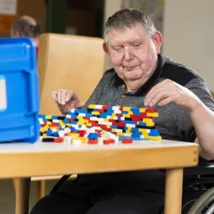 Ein Mann sitzt am Tisch und spielt mit Lego