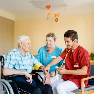 Pfleger misst Blutdruck bei Mann im Rollstuhl