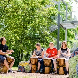 Drei Kinder und ein Lehrer trommeln