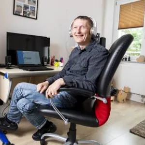 Ein Mann mit Kopfhörer sitzt an einem Schreibtisch