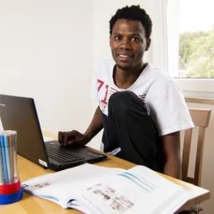 Ein Mann sitzt am Tisch mit einem Laptop