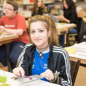 Eine Frau sitzt am Schreibtisch und lacht