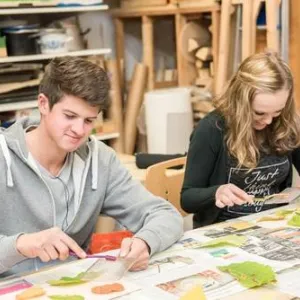 Zwei Menschen sitzen an einem Tisch und arbeiten