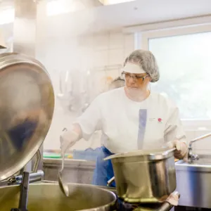 Eine Frau steht in der Küche an einem kochenden Topf