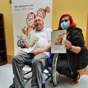 Pfelgerin mit Mann im Rollstuhl