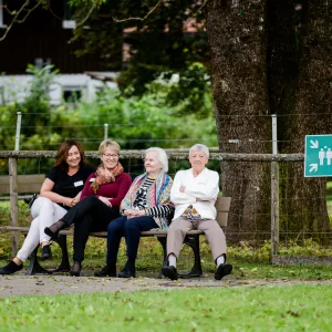 Senior*innen und Mitarbeitende auf Parkbank 
