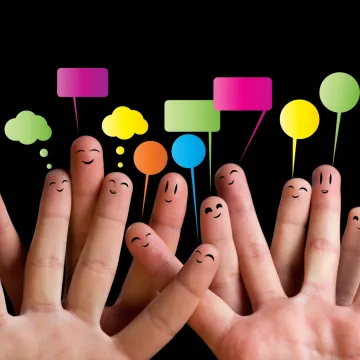 Vier hochgehaltene Hände mit bunten Fähnchen dahinter