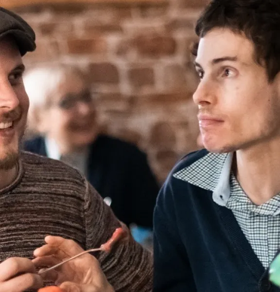 Junger Mann mit Behinderung isst mit seinem Betreuer ein Eis