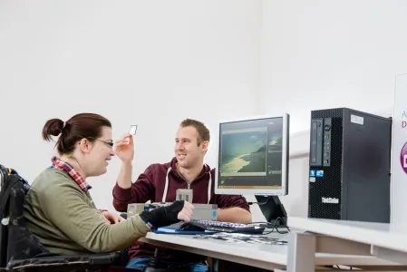 Zwei Menschen sitzen vor einem Computer