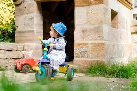 Krippenkind beim Dreiradfahren
