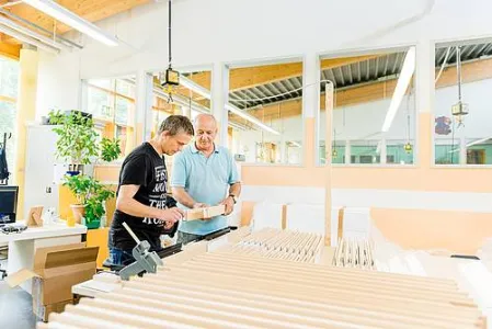 Zwei Menschen arbeiten in einer Werkstatt für Menschen mit Behinderung mit Holz