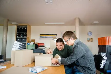 Zwei Menschen sitzen an einem Tisch und arbeiten