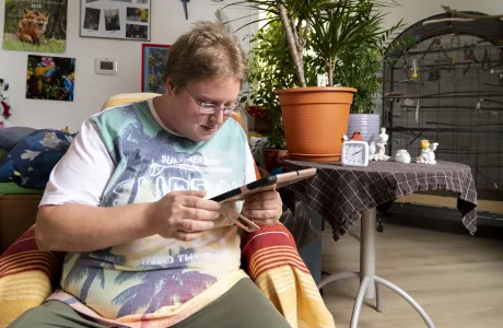 Ein Mann sitzt in einem Sessel mit einem Tablet