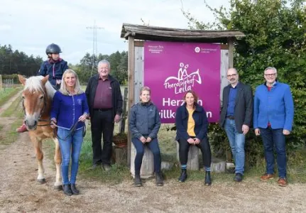 Sechs Menschen stehen und ein Kind sitzt auf einem Pferd