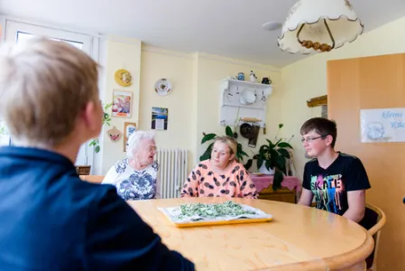Zwei alte Frauen und ein Schüler sitzen an einem Tisch