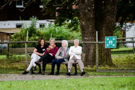Senior*innen und Mitarbeitende auf Parkbank 