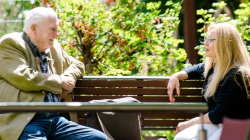 Älterer Mann im Gespräch mit Frau des Hospizvereins auf einer Bank