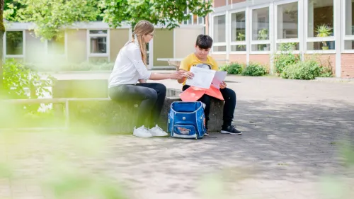 Schüler mit Lehrerin vor Schule