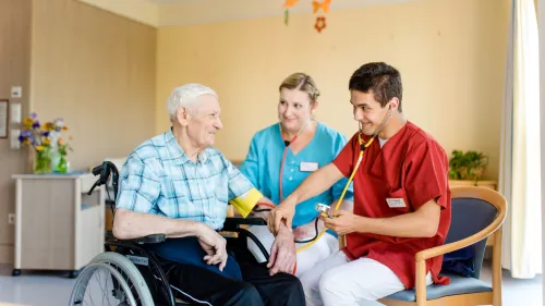 Ein Mann im Rollstuhl mit zwei an anderen Menschen