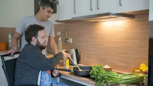 Mann im Rollstuhl kocht in der Küche