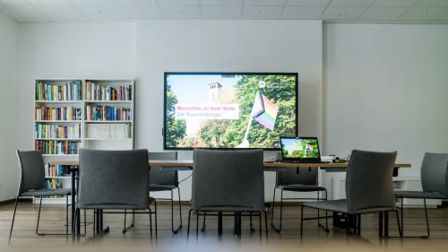 Bilschirm, Tisch und Stühle davor