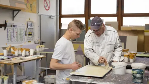 Ein Azubi und ein Ausbilder malen etwas an