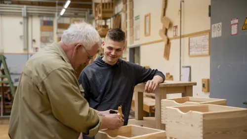 Ein Azubi und ein Ausbilder arbeiten an einer Holzbox