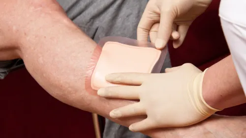 Eine Person mit Handschuhen klebt ein Pflaster auf