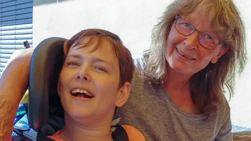 Ein junger Mann im Rollstuhl mit einer lachenden Frau