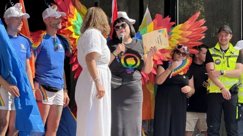 „Besondere Gruppe 2025“ – so darf sich der bunte Festumzug der Rummelsberger Diakonie am CSD in Nürnberg nennen. Marion Raspiller, Leiterin der Abteilung Marketing, nimmt die Urkunde auf der Bühne am Kornmarkt entgegen.